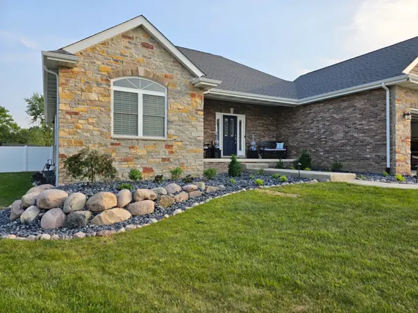 Homeowner standing in a backyard reviewing landscape design plans, representing the best way to plan a landscaping project with Dean's Pools and Landscaping